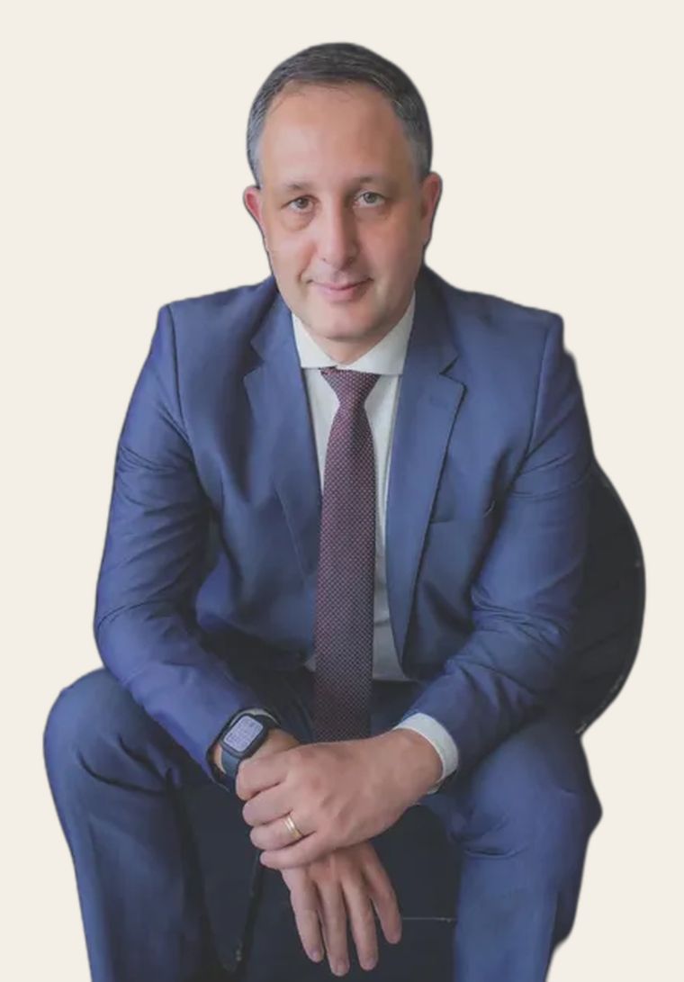 Professor Leonardo Cremasco, de terno azul, olhando para a câmera